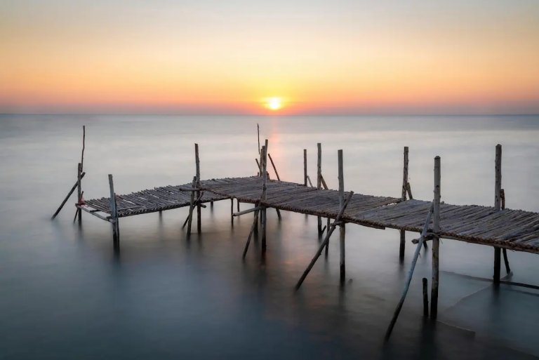 Minimal seascape with wooden pier at sunrise, illustrating patience and timing in photography
