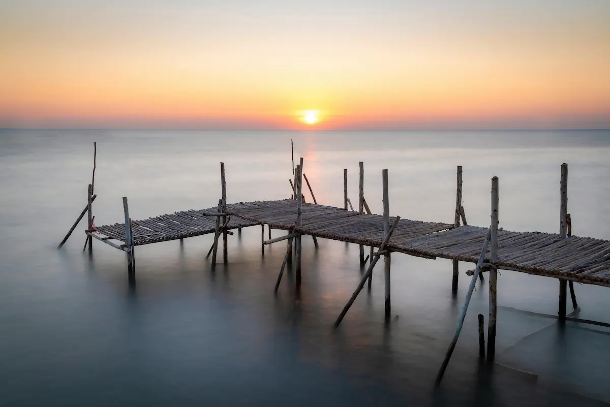 Minimal seascape with wooden pier at sunrise, illustrating patience and timing in photography